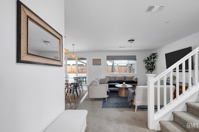 carpeted living area featuring stairway and visible vents