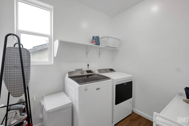 washroom featuring washing machine and clothes dryer, baseboards, dark wood-style flooring, and laundry area