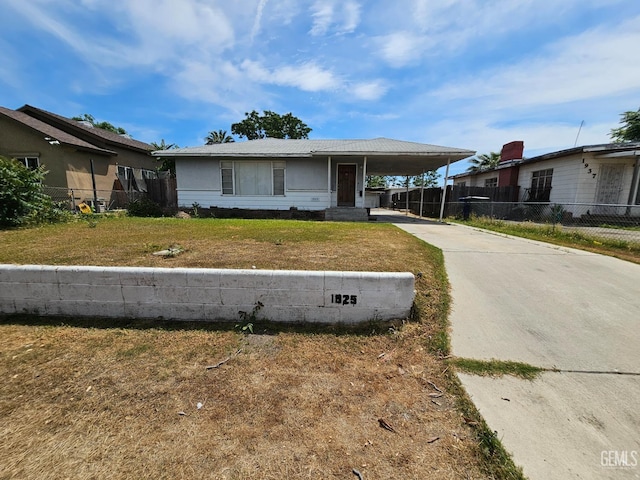 view of front of house with fence, driveway, a front yard, and a carport