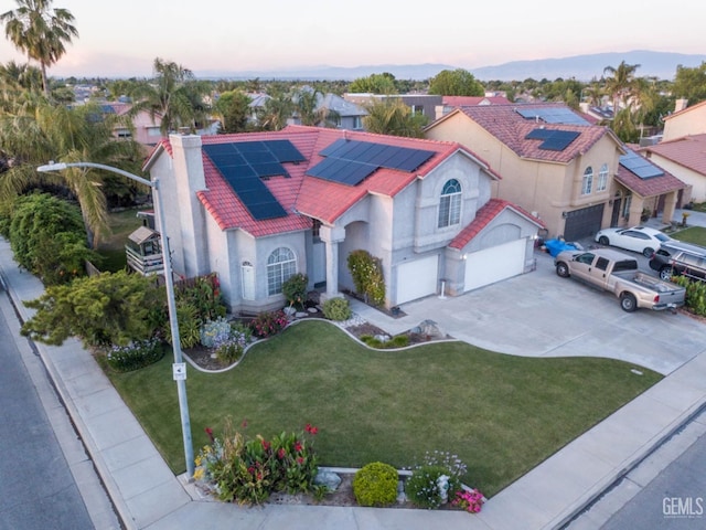 view of front of property featuring a tile roof, a chimney, stucco siding, a lawn, and a garage