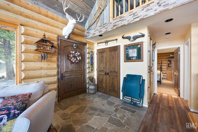 foyer featuring rustic walls and a towering ceiling