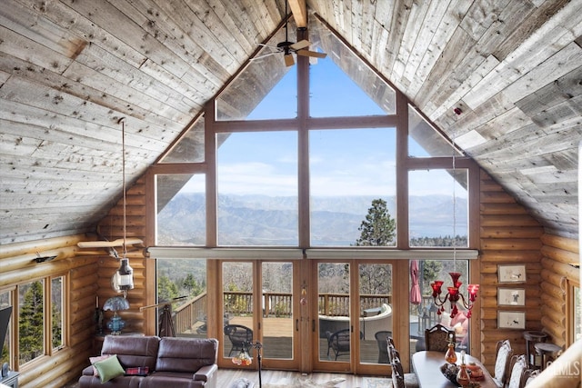 living area with high vaulted ceiling, plenty of natural light, expansive windows, and a mountain view