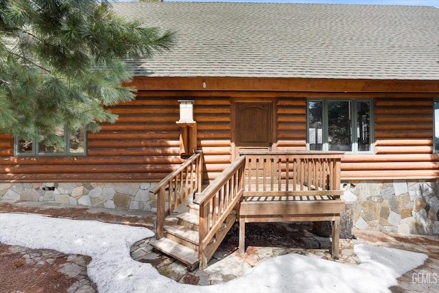 entrance to property with a shingled roof and log exterior