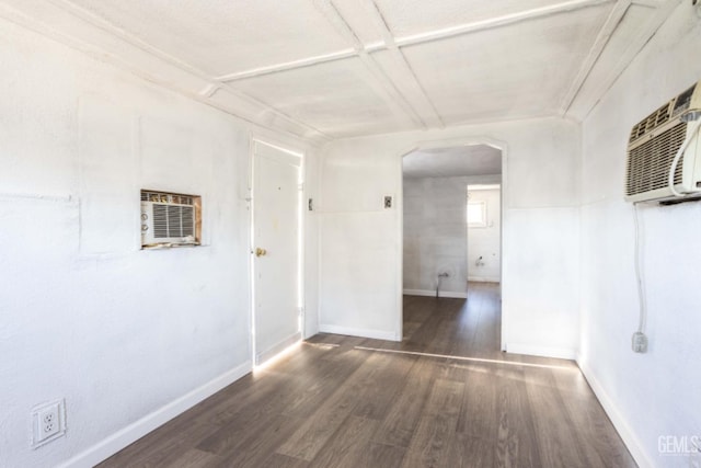 unfurnished room featuring dark wood-type flooring, coffered ceiling, and a wall mounted air conditioner