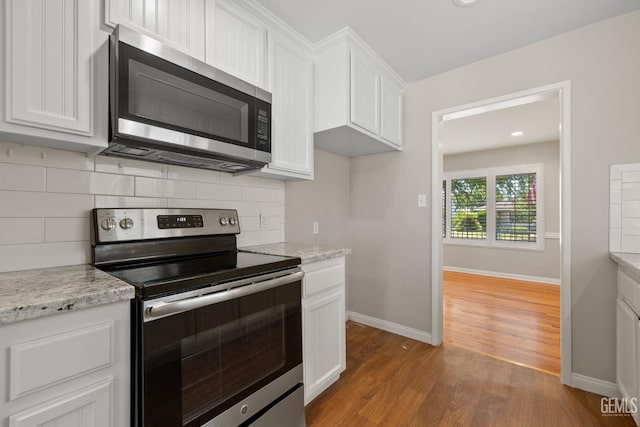 2613 Spruce St, Bakersfield, CA 93301 - kitchen with appliances with stainless steel finishes, wood finished floors, white cabinets, baseboards, and tasteful backsplash
