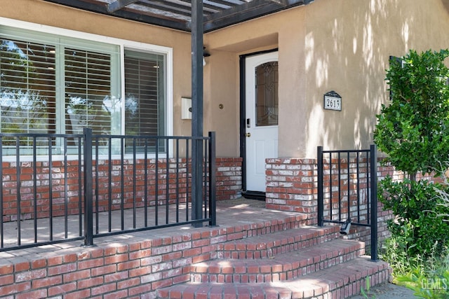 2613 Spruce St, Bakersfield, CA 93301 - view of exterior entry featuring stucco siding and a pergola