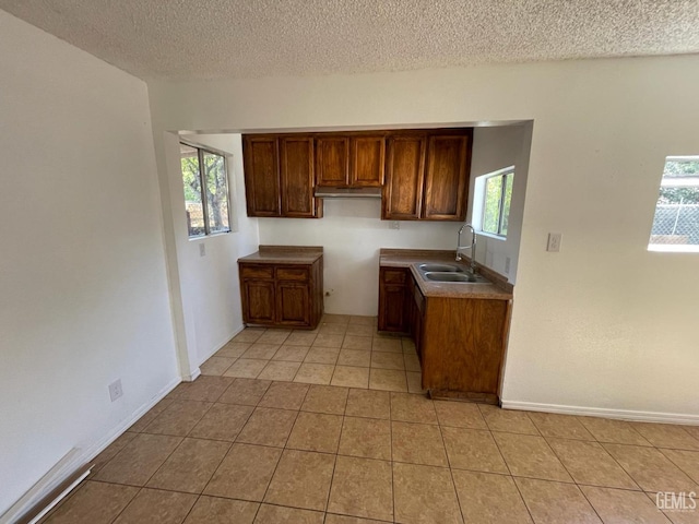 kitchen with light tile patterned floors, a textured ceiling, and sink