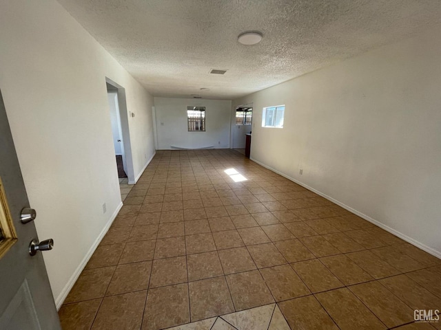 spare room with a textured ceiling and tile patterned floors