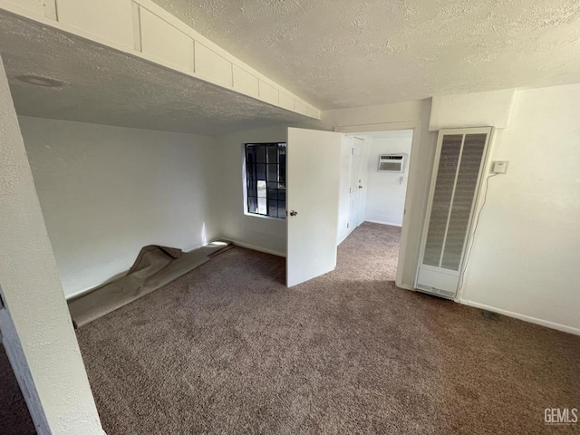 unfurnished room with a textured ceiling, dark carpet, and an AC wall unit