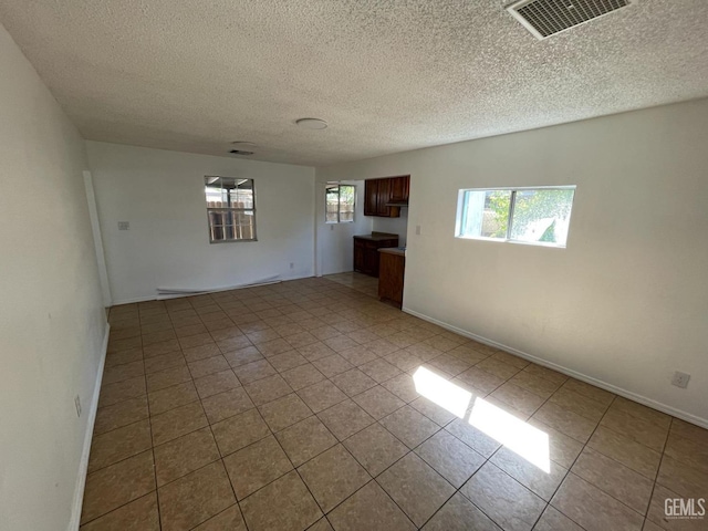 spare room featuring a textured ceiling and light tile patterned flooring