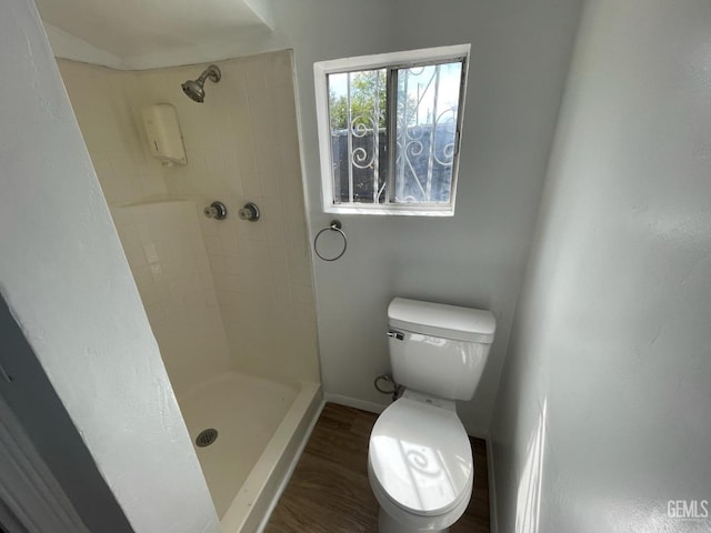 bathroom featuring tiled shower, hardwood / wood-style flooring, and toilet