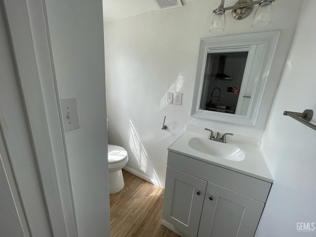 bathroom featuring vanity, hardwood / wood-style flooring, and toilet