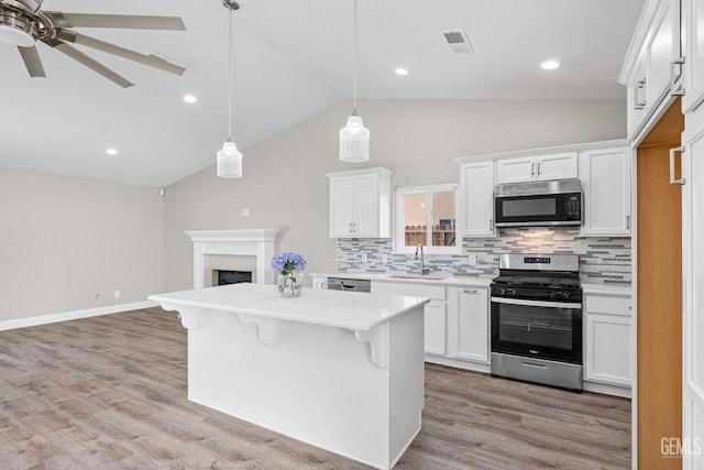 kitchen with visible vents, decorative backsplash, lofted ceiling, a sink, and stainless steel appliances