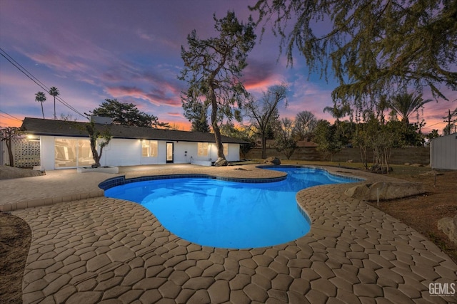 pool at dusk featuring a patio area