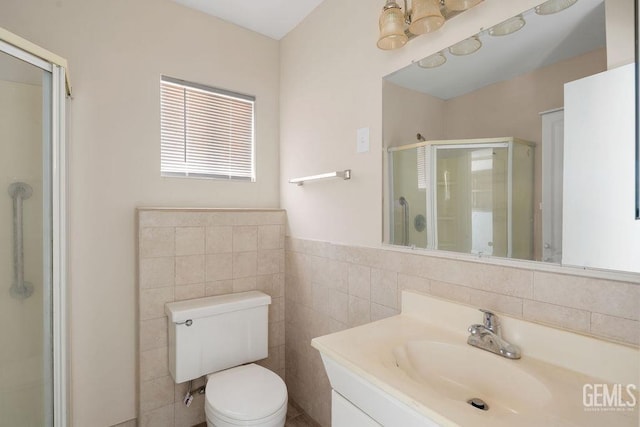 bathroom featuring vanity, toilet, tile walls, and a shower with shower door