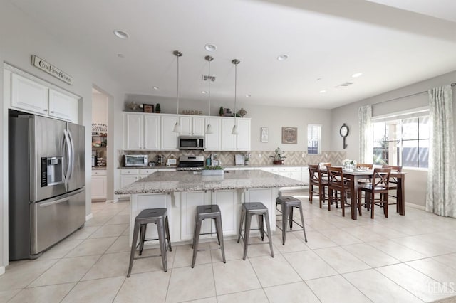 kitchen with decorative backsplash, appliances with stainless steel finishes, white cabinetry, and a kitchen island