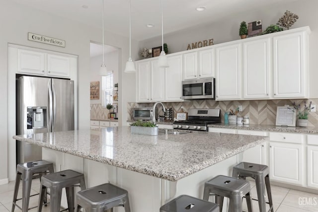 kitchen with light tile patterned floors, white cabinetry, stainless steel appliances, and pendant lighting