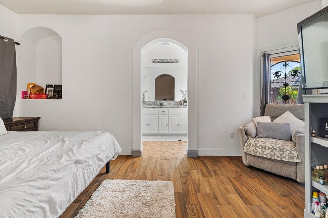 605 Cornelia St, Wasco, CA 93280 - bedroom with wood finished floors, connected bathroom, and arched walkways