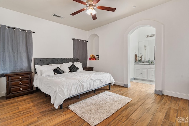 605 Cornelia St, Wasco, CA 93280 - bedroom featuring light wood-style floors, ensuite bathroom, arched walkways, and ceiling fan