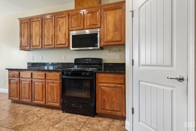 605 Cornelia St, Wasco, CA 93280 - kitchen featuring stainless steel microwave, black gas range oven, brown cabinetry, and dark stone countertops