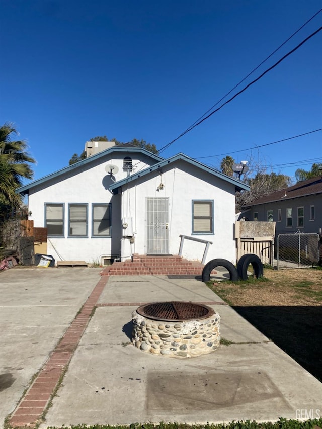 rear view of house with a fire pit and a patio area