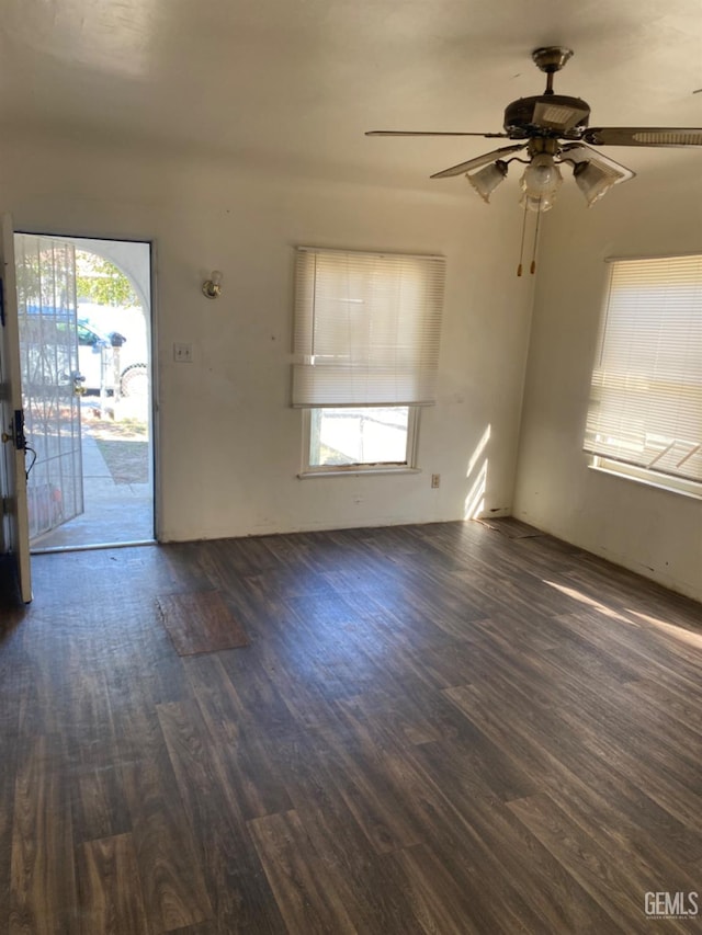 unfurnished living room featuring plenty of natural light, ceiling fan, and dark hardwood / wood-style floors