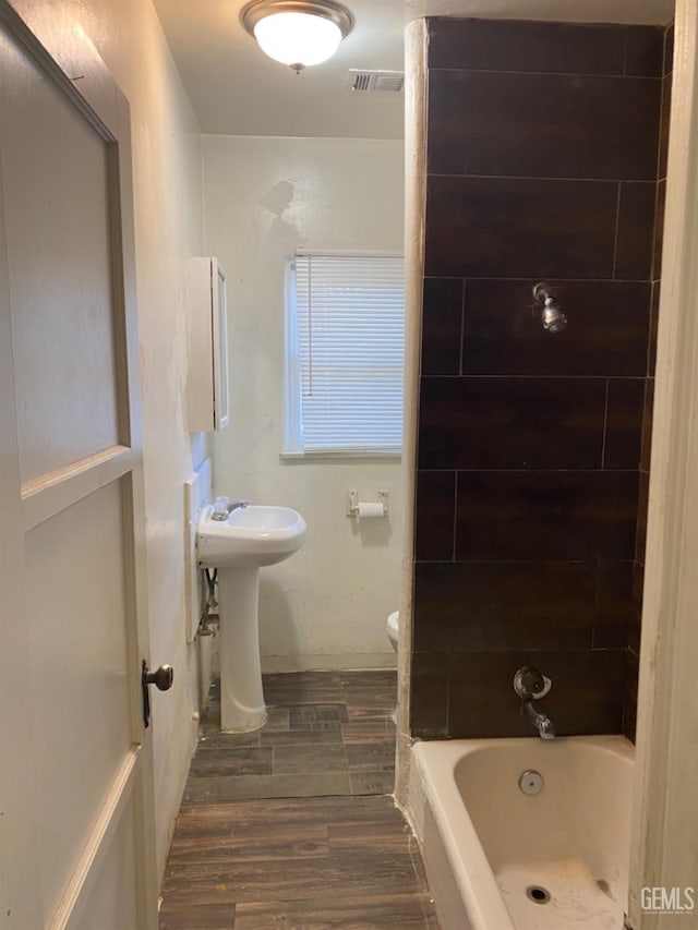 full bathroom with toilet, sink, washtub / shower combination, and hardwood / wood-style floors