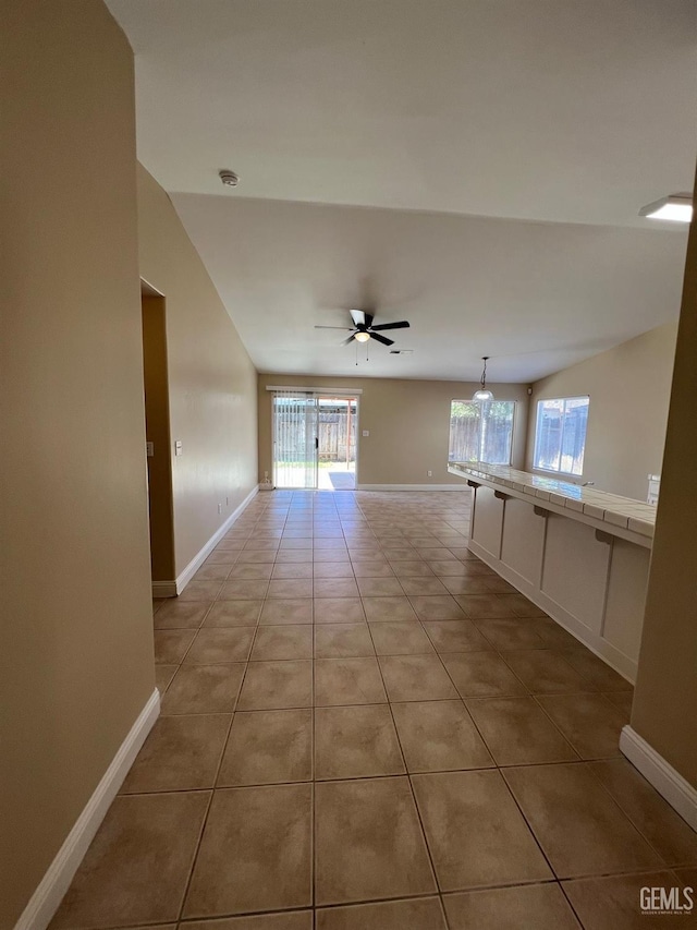 hallway with baseboards, a wealth of natural light, and light tile patterned flooring