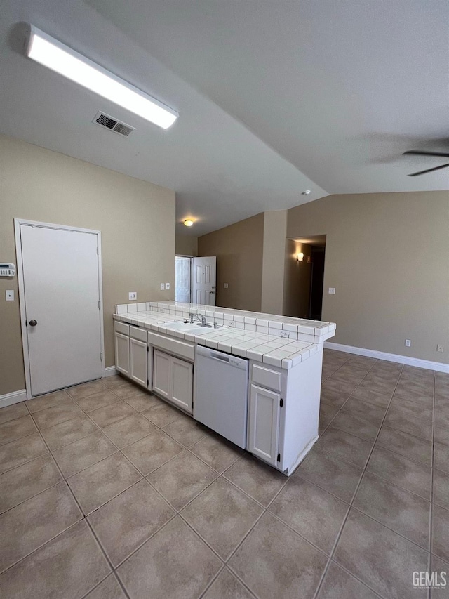 kitchen with tile countertops, lofted ceiling, a sink, visible vents, and dishwasher