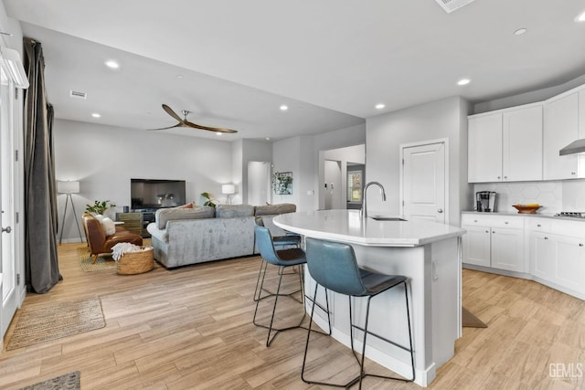 kitchen with a sink, light wood-type flooring, a kitchen breakfast bar, and white cabinetry