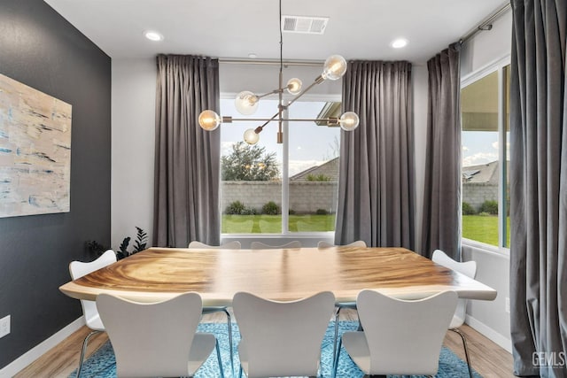 dining space featuring light wood-style flooring, baseboards, visible vents, and a wealth of natural light