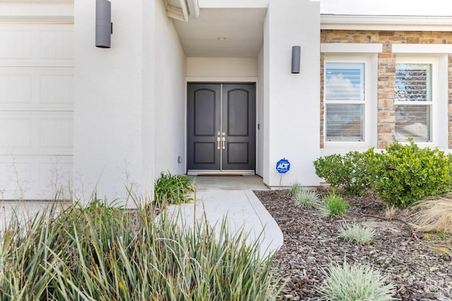 entrance to property with an attached garage and stucco siding