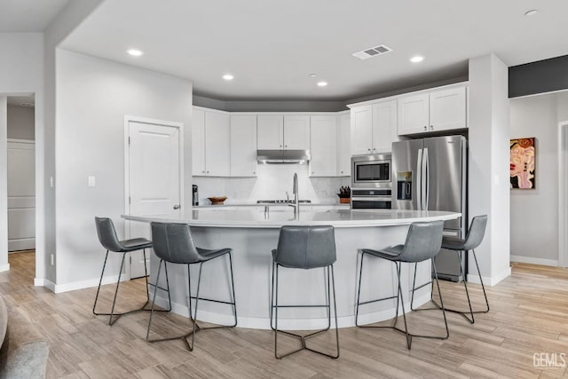 kitchen featuring light wood-type flooring, visible vents, white cabinetry, appliances with stainless steel finishes, and light countertops