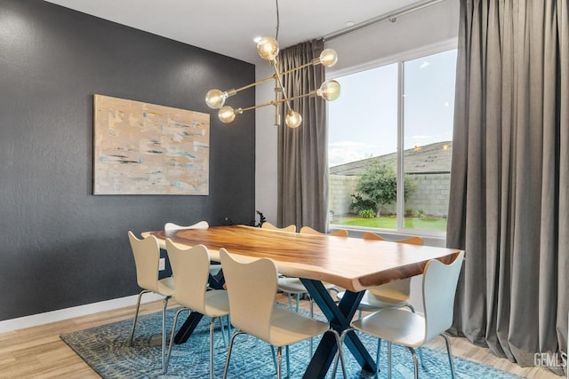 dining room featuring an inviting chandelier, wood finished floors, baseboards, and a textured wall