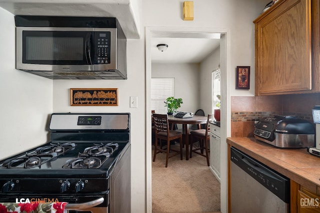 2209 Barnett St, Bakersfield, CA 93308 - kitchen with stainless steel appliances, light colored carpet, and brown cabinetry