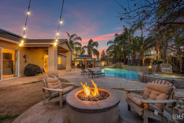 pool at dusk with an in ground hot tub, a gazebo, a patio area, and a fire pit