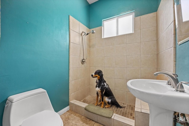 bathroom with tiled shower, tile patterned floors, toilet, and sink