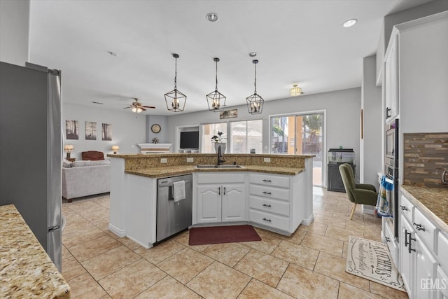 kitchen with decorative light fixtures, sink, white cabinets, kitchen peninsula, and stainless steel appliances