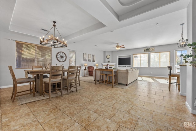 dining area featuring a raised ceiling, light tile patterned flooring, and ceiling fan with notable chandelier