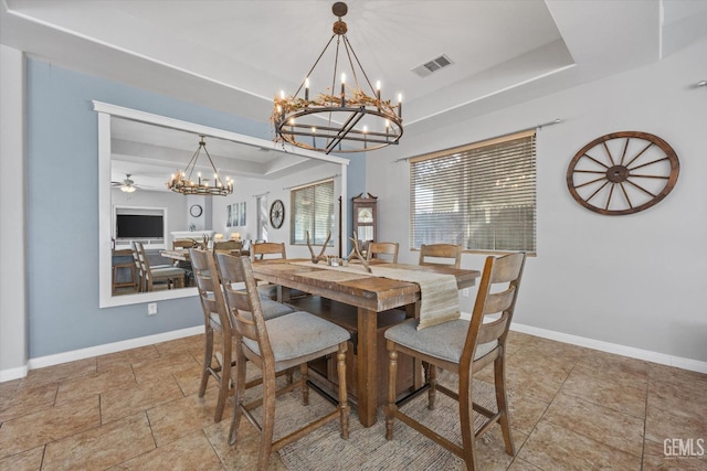 dining area featuring a raised ceiling and ceiling fan with notable chandelier