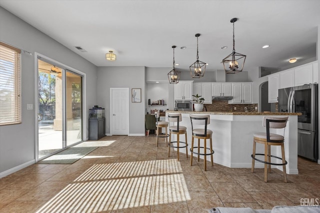 kitchen with pendant lighting, tasteful backsplash, white cabinetry, a kitchen bar, and stainless steel appliances