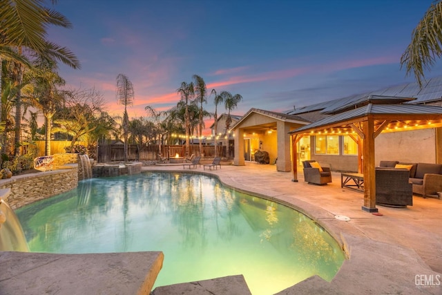 pool at dusk with a gazebo, pool water feature, an outdoor living space, and a patio area