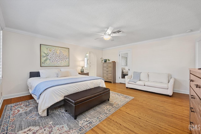 bedroom featuring arched walkways, light wood-style flooring, and ornamental molding