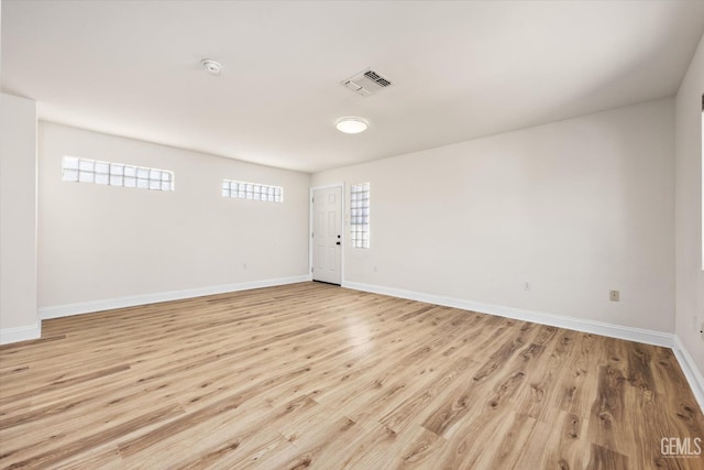 unfurnished room featuring visible vents, light wood-style flooring, and baseboards