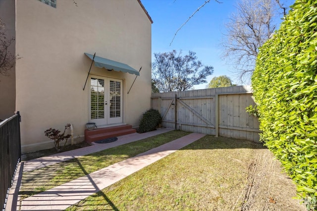 view of yard featuring french doors, fence, entry steps, and a gate