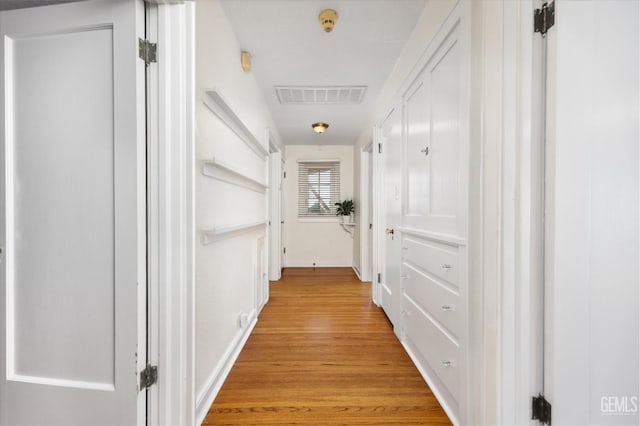 hall featuring visible vents, light wood-type flooring, and baseboards