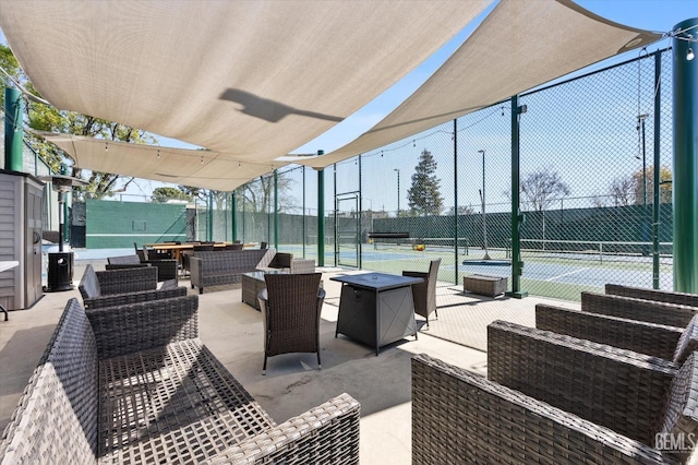 view of patio / terrace featuring a tennis court, an outdoor living space, and fence