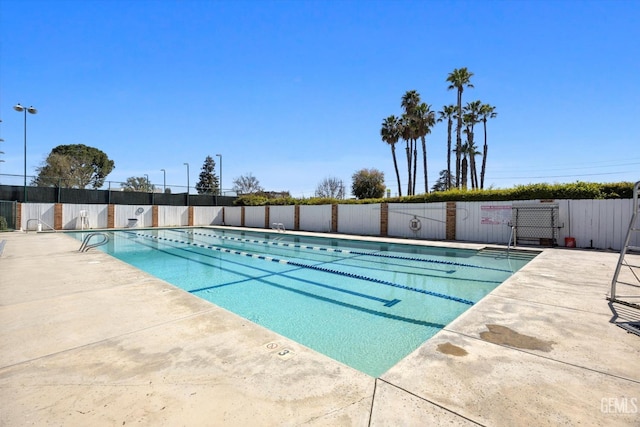 community pool with a patio and fence