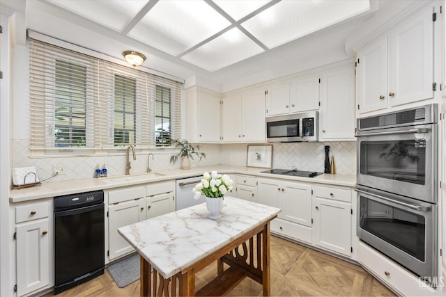 kitchen featuring white cabinetry, stainless steel appliances, light countertops, and a sink