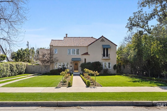 mediterranean / spanish-style house with stucco siding, fence, a front yard, a chimney, and a tiled roof